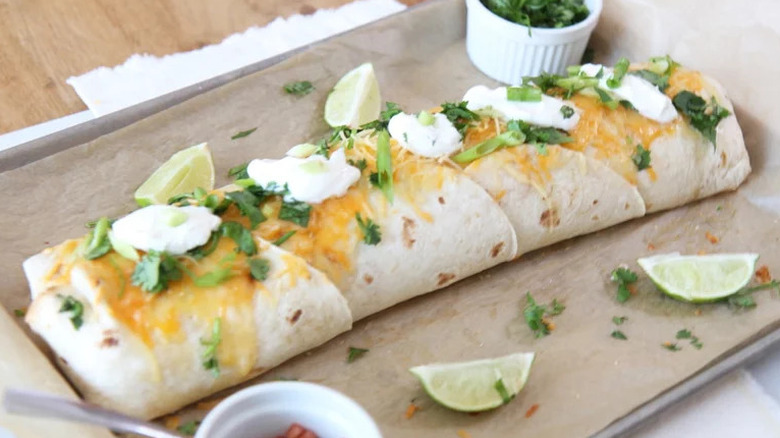 Giant Burrito on parchment-lined baking tray with limes