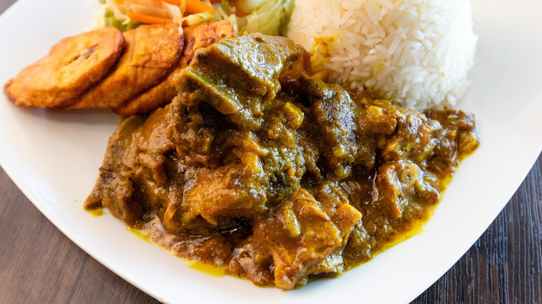 Goat curry on plate with rice and vegetables