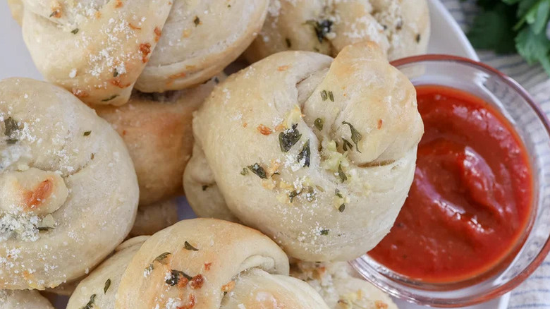 Close up of garlic knots with marinara dip on the side