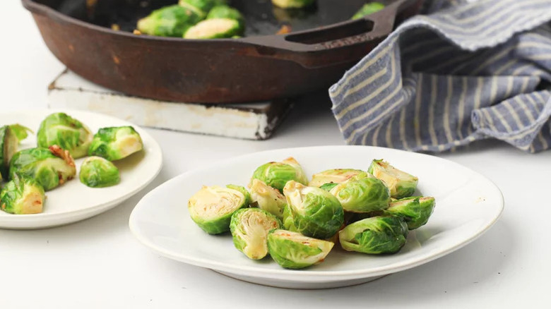 White plate filled with Brussels sprouts with more in the back