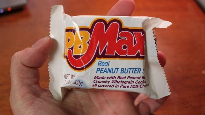 A hand holding a bagged PB Max candy bar.
