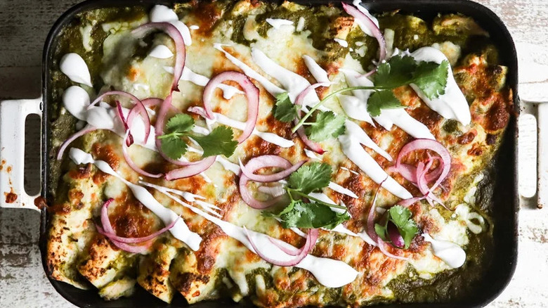 Cheesy Salsa Verde Chicken Enchiladas in black baking dish