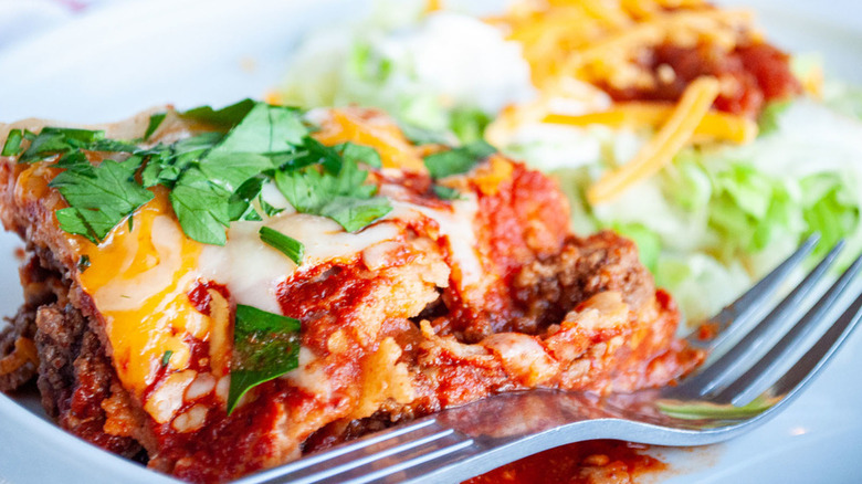 Enchilada Casserole on white dish with salad and fork