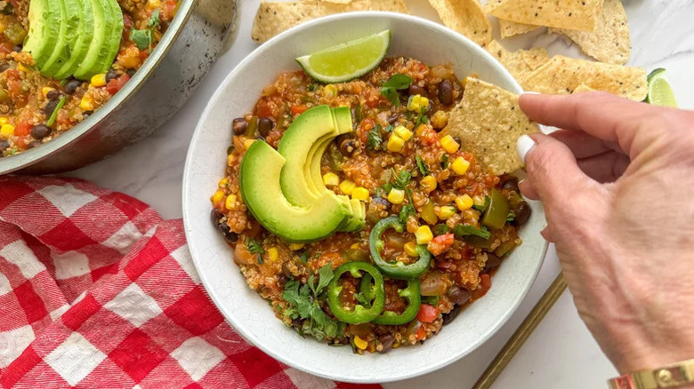 One-Pan Quinoa Enchilada Skillet in white bowl with avocados and jalapenos