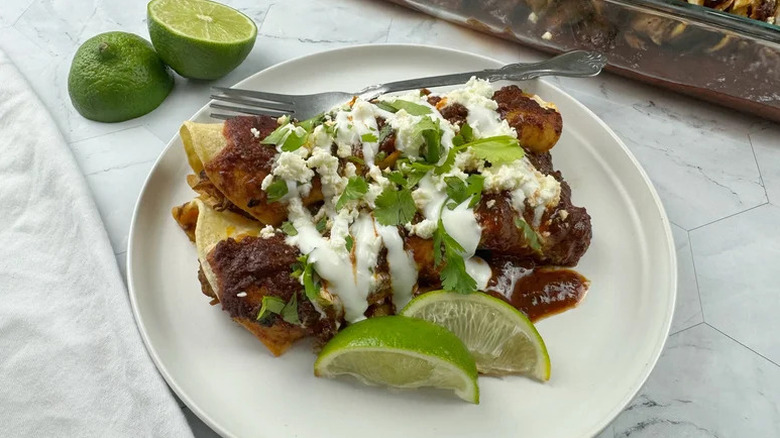 Pork Enchiladas Rojas on white plate with limes