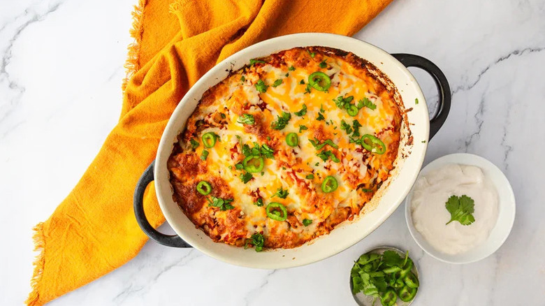 Vegetarian Jackfruit Enchiladas in white casserole dish with yellow towel