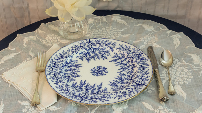 dinner table with doily, silverware, and flower