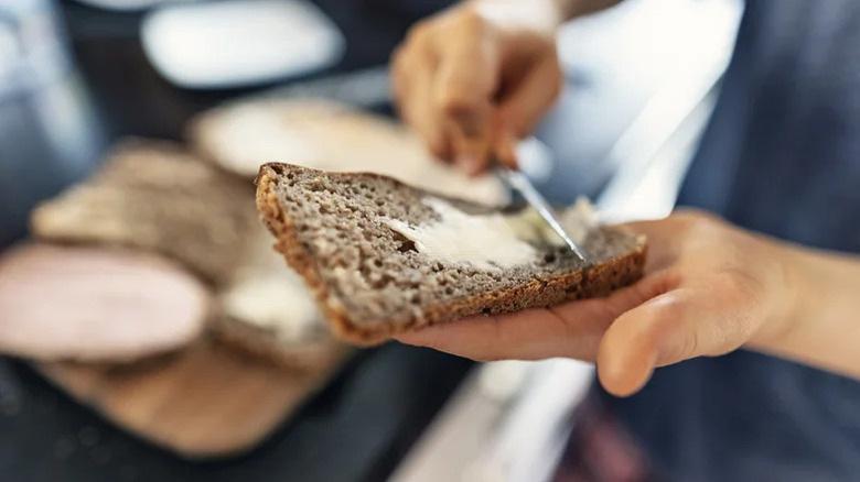 Hands adding butter to slice of bread