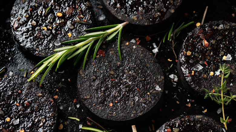 A closeup of cooked and sliced black pudding with herbs over the top