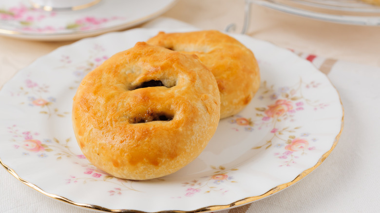 Two Eccles cakes laid on top of each other on an ornate dish