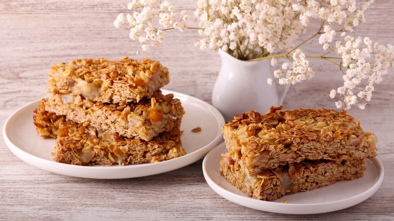 Flapjacks shown on two separate dishes with flowers shown in the background