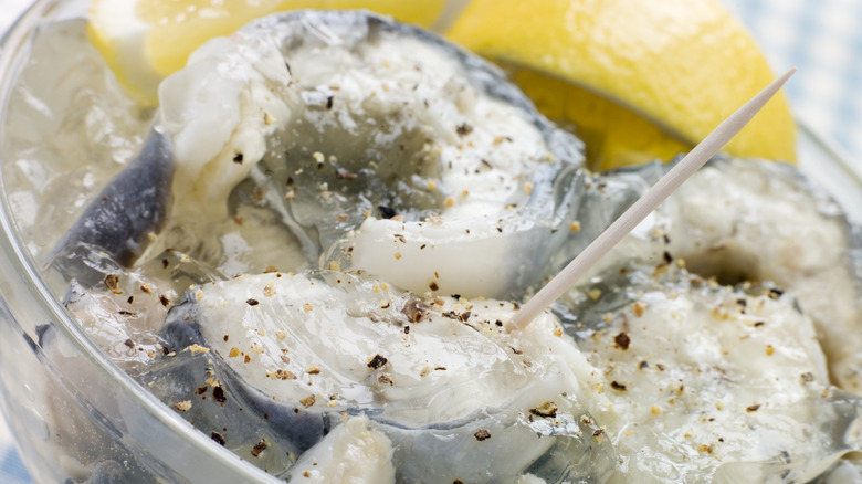 A closeup of jellied eels in a bowl with a lemon in the background