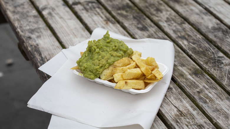 Mushy peas in a polystyrene container along with thick cut chips