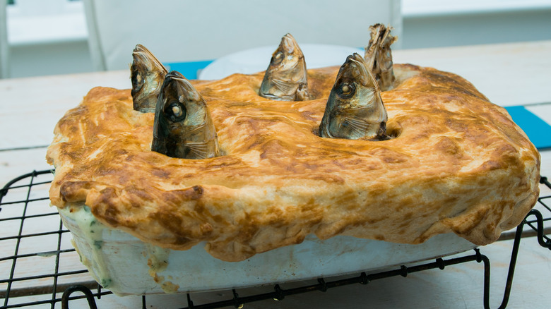 A stargazy pie on a baking rack with five fish heads poking out