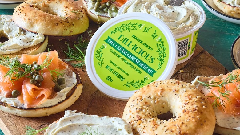 Tub of Trader Joe's Dill-icious Cream Cheese Spread surrounded by bagels, lox, capers, dill