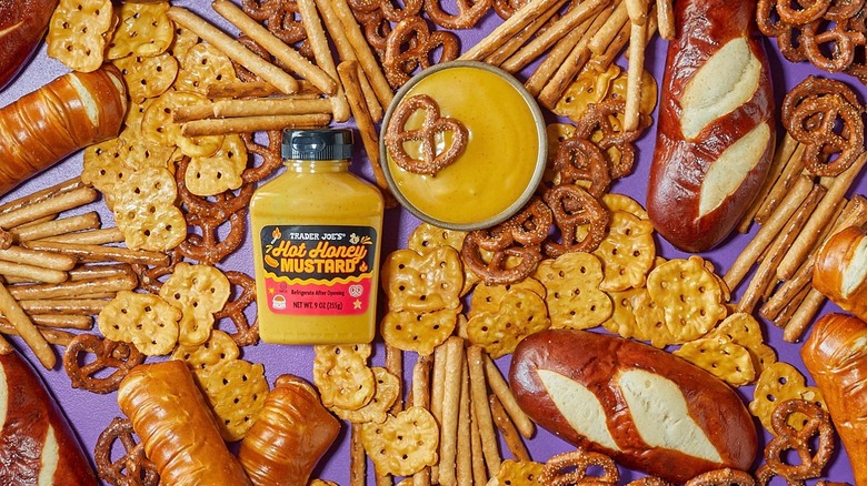 Bottle of Trader Joe's Hot Honey Mustard next to bowl of mustard, surrounded by various forms of pretzels