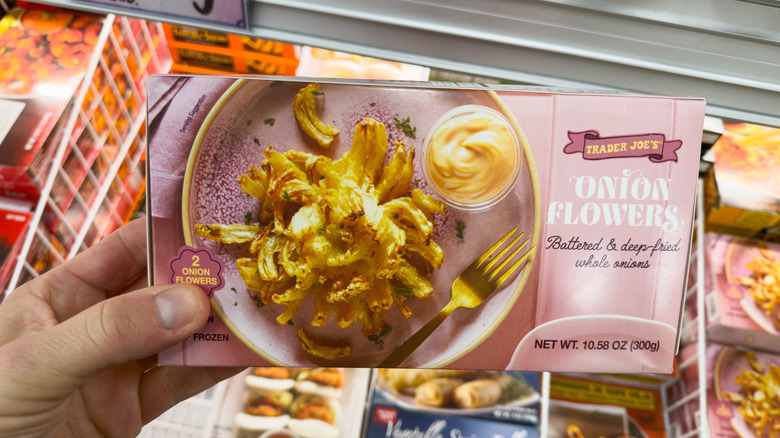 Hand holding box of Trader Joe's Onion Flowers above freezer at the store