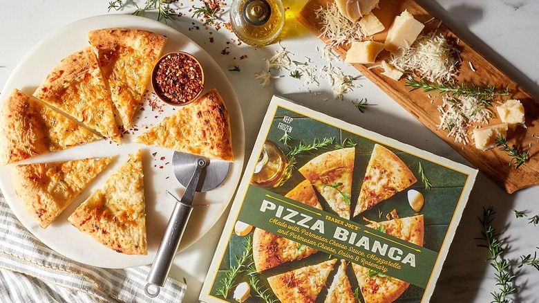 Trader Joe's Pizza Bianca box next to cut pizza on plate, board with cheese and rosemary sprigs