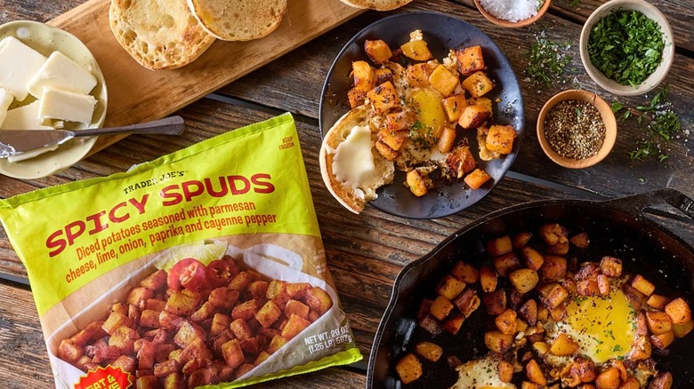 Bag of Trader Joe's Spicy Spuds next to cast-iron skillet with potatoes and eggs