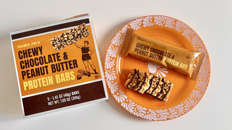 Box of Chewy chocolate and Peanut Butter Protein Bars with one piece on a plate