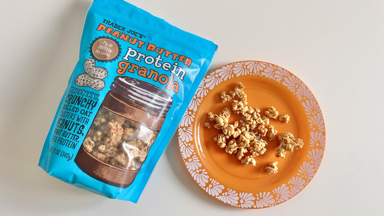 Chunks of Trader Joe's peanut butter protein granola on a plate with a whole bag next to it
