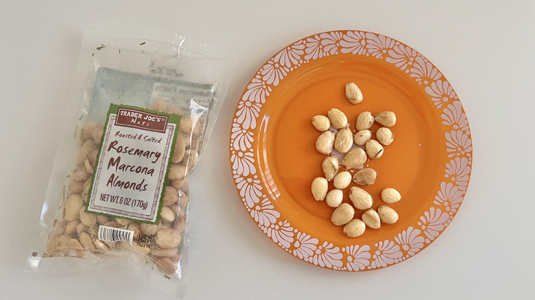 Handful of Roasted & Salted Rosemary Marcona Almonds next to a bag of almonds