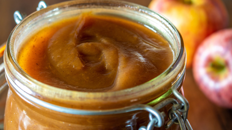 Close up of apple butter in jar, two apples in background