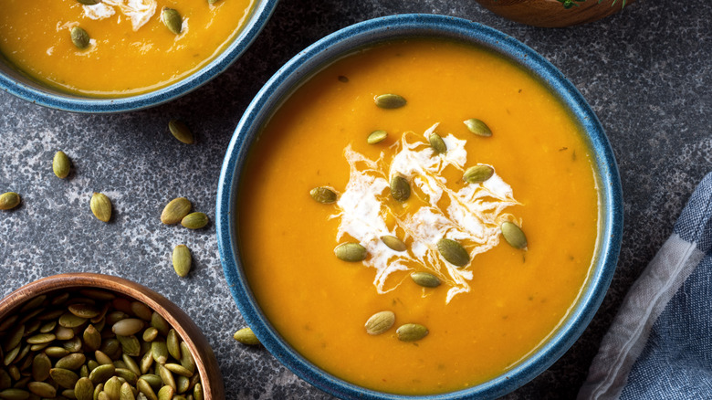 Overhead shot of soup topped with pumpkin seeds and cream