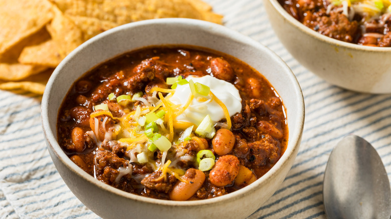Bowl of chili topped with sour cream, cheese, and green onions
