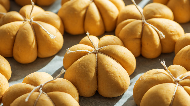 Unbaked pumpkin shaped rolls tied up with string
