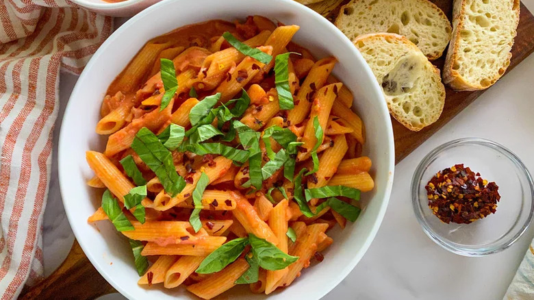 A bowl of penne alla vodka and slices of bread