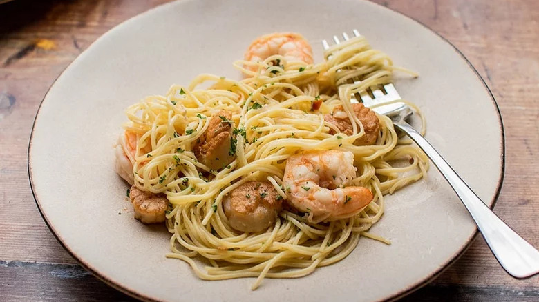 A plate of shrimp and scallop scampi over pasta