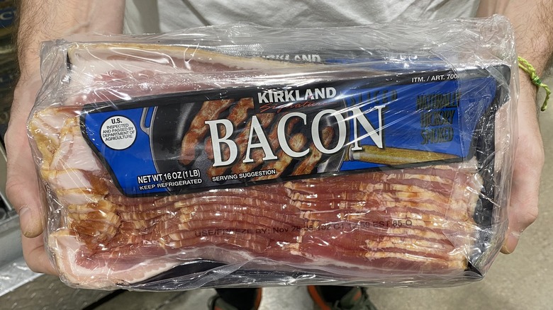 Hands holding up blue package of Kirkland Signature bacon slices