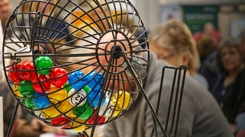 Bingo drum with colorful balls and people blurred in background
