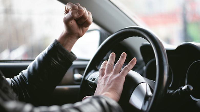 Unidentified person shaking fist and honking car horn