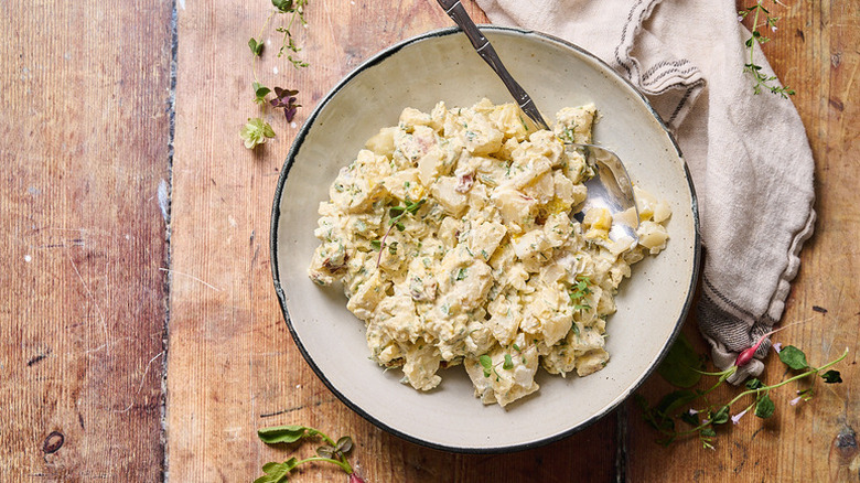 Creamy egg-potato salad on bowl with spoon