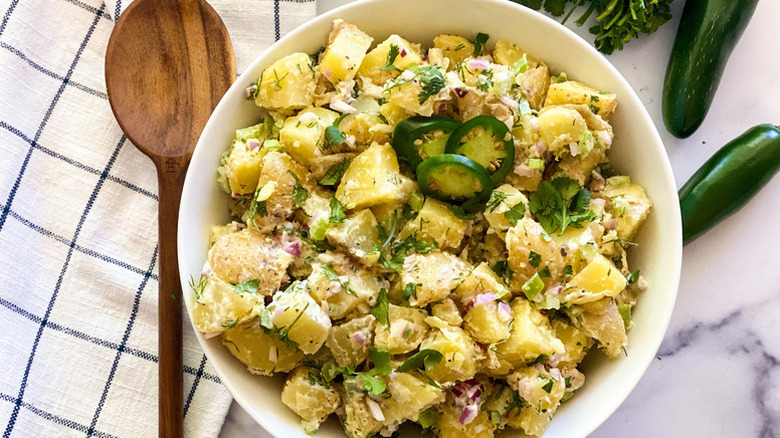 Creamy potato salad in bowl with sliced jalapeños