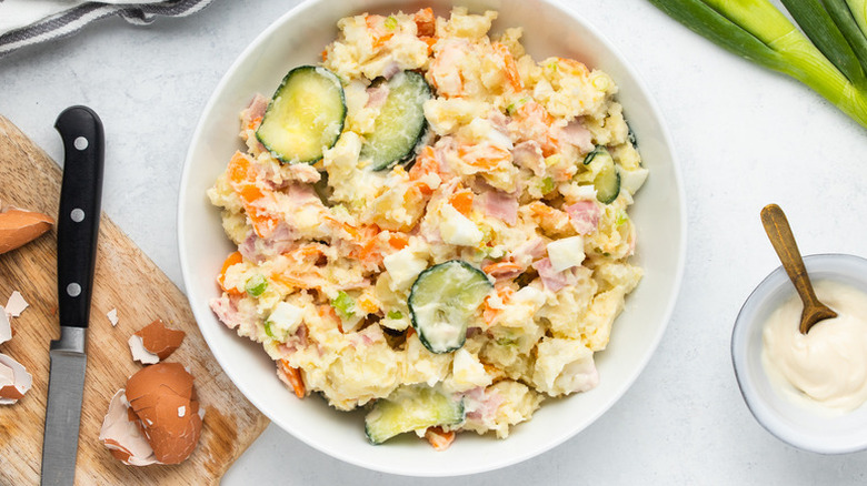 Bowl of creamy potato salad with egg and cucumber