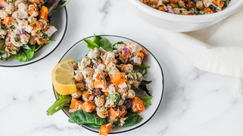 Bowl of chickpea sweet potato salad with lemon wedge