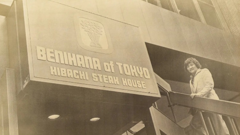 A photograph of Hiroaki Aoki standing outside a Benihana restaurant