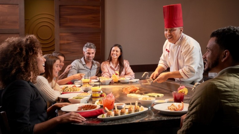A wide shot of diners sitting around the table while a Benihana chef cooks their food
