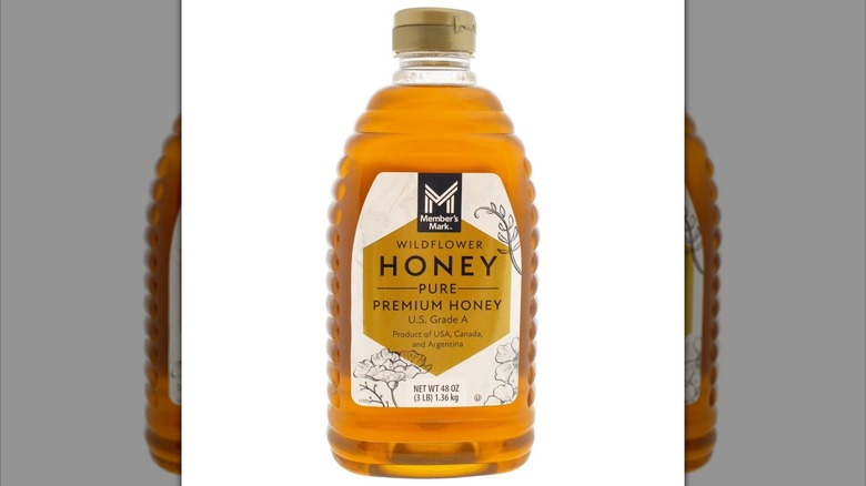 Plastic bottle of honey with illustrations of flora on label