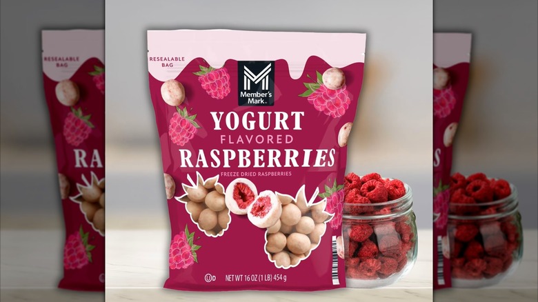 Bag of yogurt covered raspberries on countertop with glass jar of raspberries