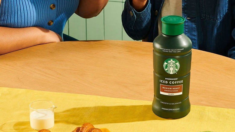 Bottle of iced coffee on table in front of man and woman