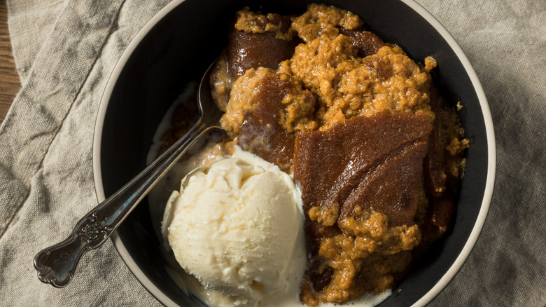 Indian pudding in bowl with a scoop of vanilla ice cream