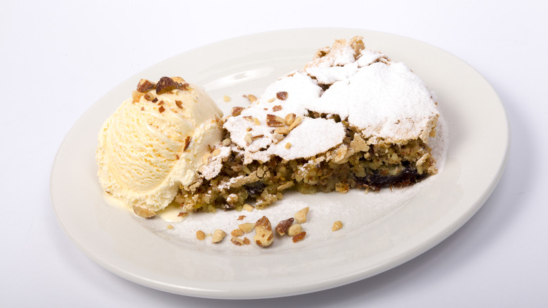 A nut pie with a scoop of ice cream on a white plate