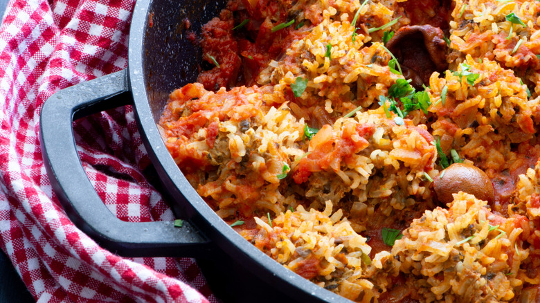 Porcupine meatballs in skillet beside a red and white checkered cloth