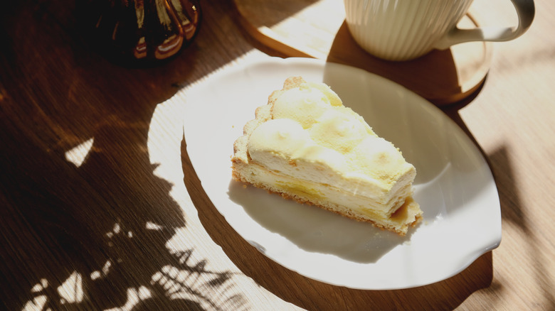 A pie slice on a white plate on a table in sunlight