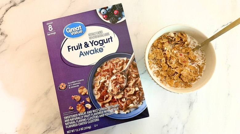 Box of Great Value Fruit & Yogurt Awake cereal next to bowl of cereal with spoon on marble surface