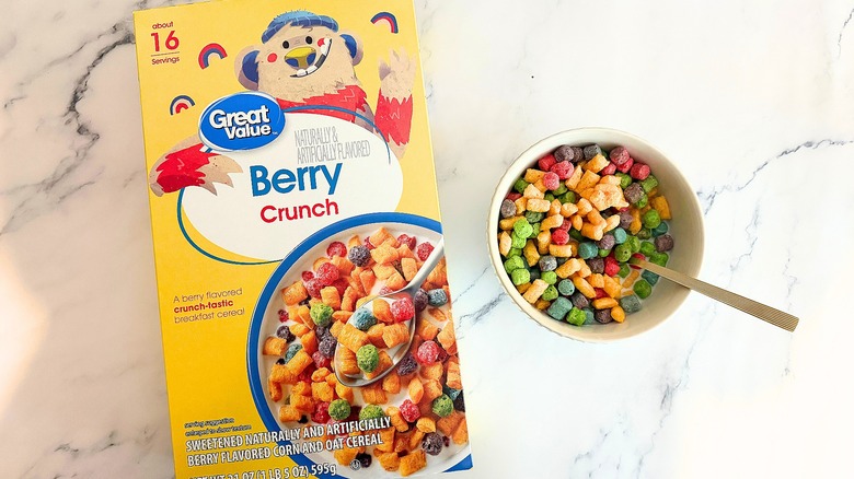 Box of Great Value Berry Crunch cereal next to bowl of cereal with spoon on marble surface